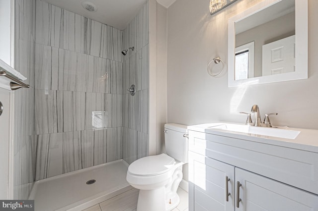 bathroom with vanity, toilet, tile patterned floors, and a tile shower