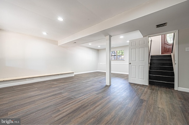 basement featuring dark wood-type flooring and a baseboard heating unit