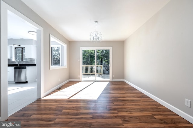 unfurnished dining area featuring a chandelier, dark wood-type flooring, and sink