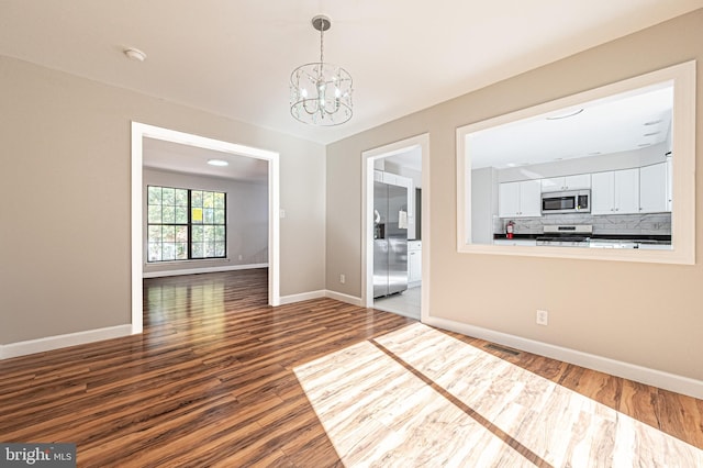 unfurnished dining area featuring a chandelier and wood-type flooring