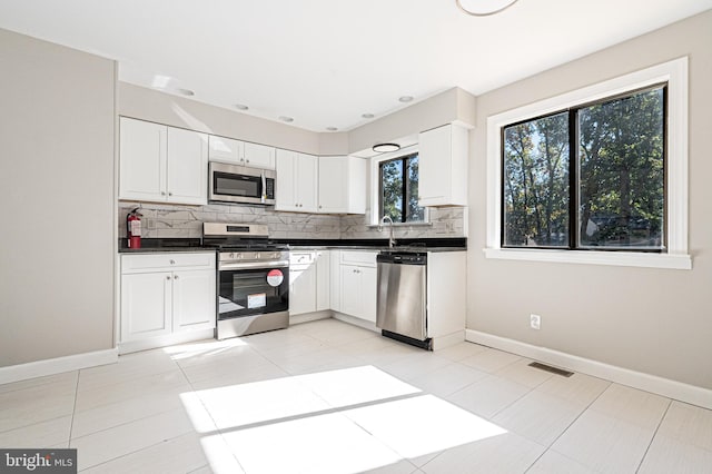 kitchen with backsplash, stainless steel appliances, and white cabinets