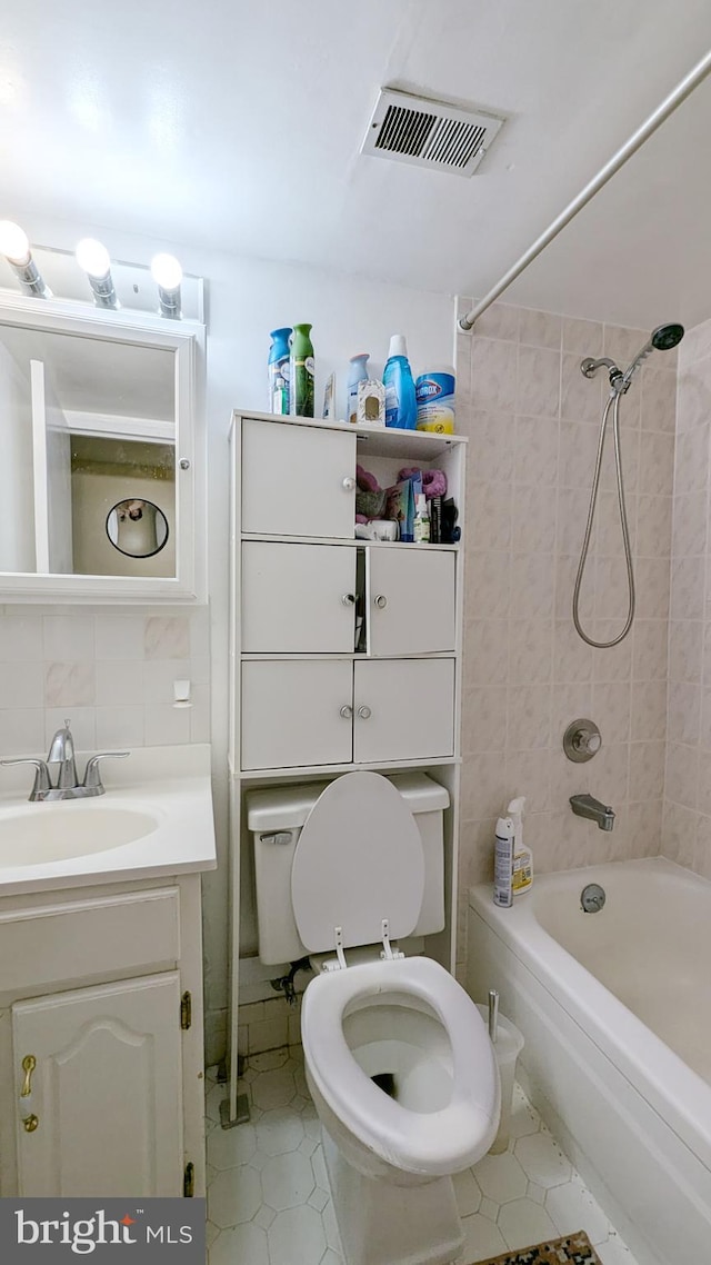 full bathroom featuring backsplash, toilet, vanity, tile walls, and tiled shower / bath