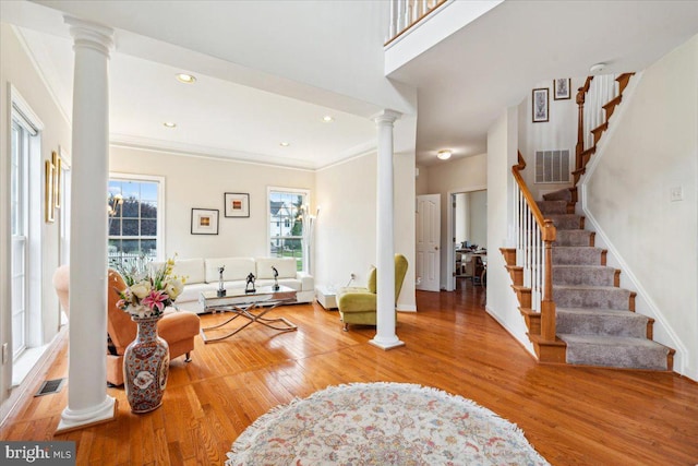 entrance foyer with ornamental molding, hardwood / wood-style floors, and decorative columns