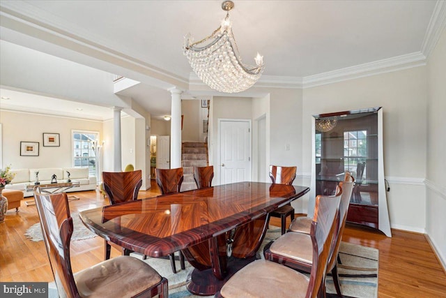 dining space with decorative columns, light hardwood / wood-style floors, and a healthy amount of sunlight