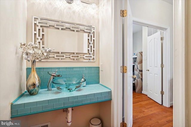 bathroom with sink, wood-type flooring, and tasteful backsplash