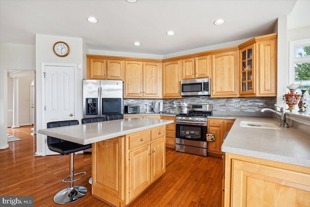 kitchen with a breakfast bar area, stainless steel appliances, dark wood-type flooring, sink, and a center island