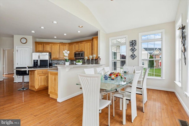 dining space with light hardwood / wood-style floors and vaulted ceiling