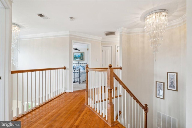 hallway featuring ornamental molding, light hardwood / wood-style flooring, and a notable chandelier