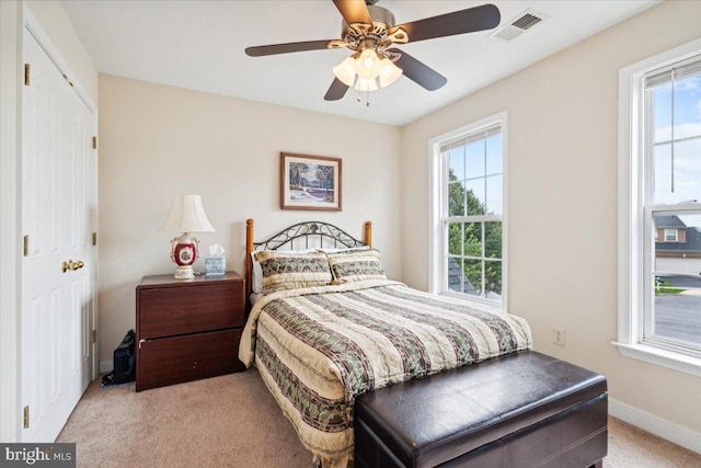 bedroom featuring light colored carpet, a closet, and ceiling fan