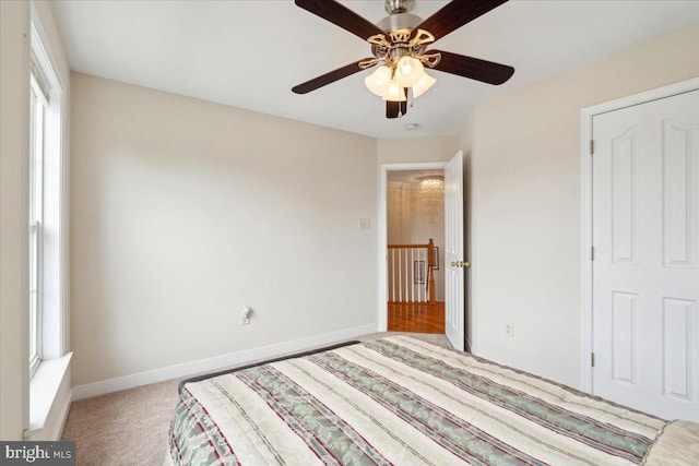 unfurnished bedroom featuring ceiling fan, multiple windows, and light colored carpet