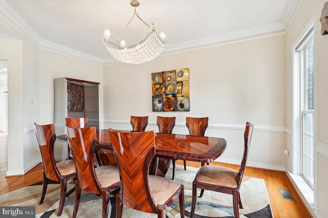 dining room featuring a notable chandelier, light hardwood / wood-style floors, and crown molding