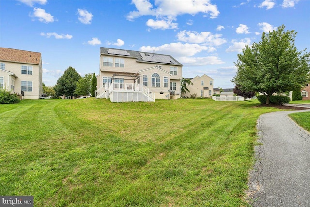 rear view of property featuring a yard and solar panels