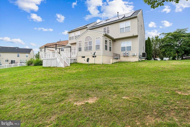 rear view of house with a wooden deck and a yard