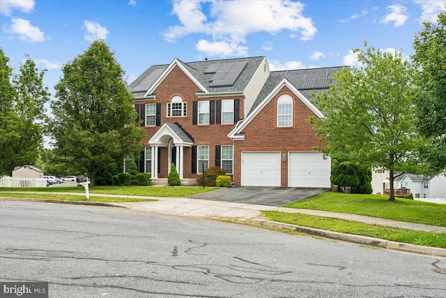 view of front of property with solar panels, a front lawn, and a garage