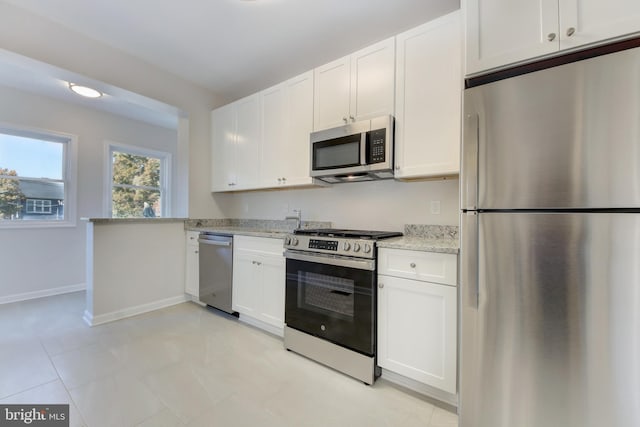 kitchen with light stone counters, white cabinets, and appliances with stainless steel finishes