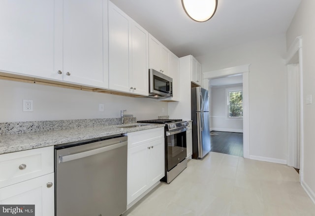 kitchen with white cabinets, sink, light stone countertops, light hardwood / wood-style floors, and stainless steel appliances