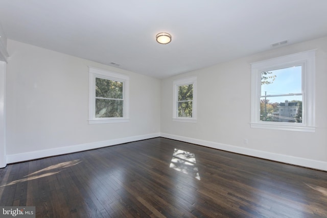 unfurnished room with a healthy amount of sunlight and dark wood-type flooring