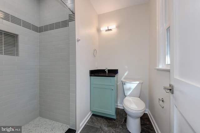 bathroom with a tile shower, vanity, and toilet