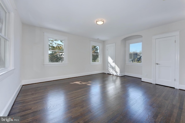 unfurnished bedroom with baseboards and dark wood-type flooring