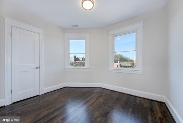 unfurnished room with dark hardwood / wood-style flooring and plenty of natural light