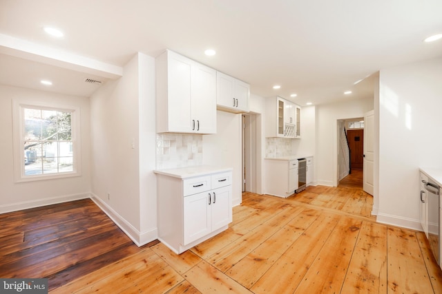 kitchen featuring decorative backsplash, white cabinetry, and light hardwood / wood-style flooring