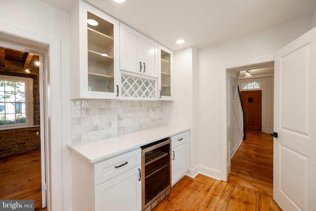 kitchen featuring wine cooler, light hardwood / wood-style flooring, white cabinets, and tasteful backsplash