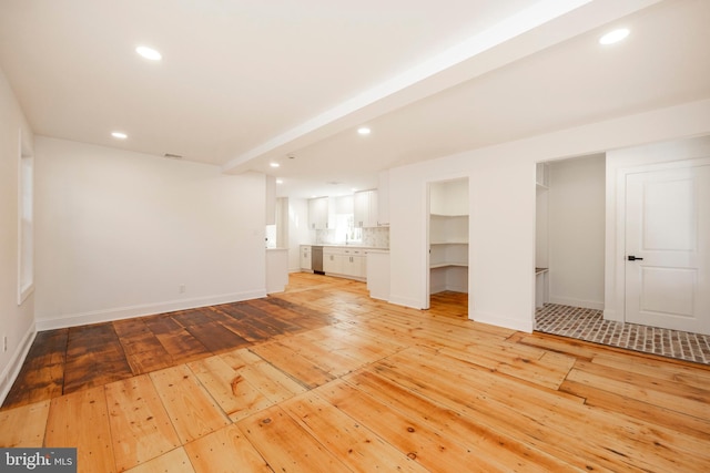 unfurnished living room featuring beam ceiling and light hardwood / wood-style flooring