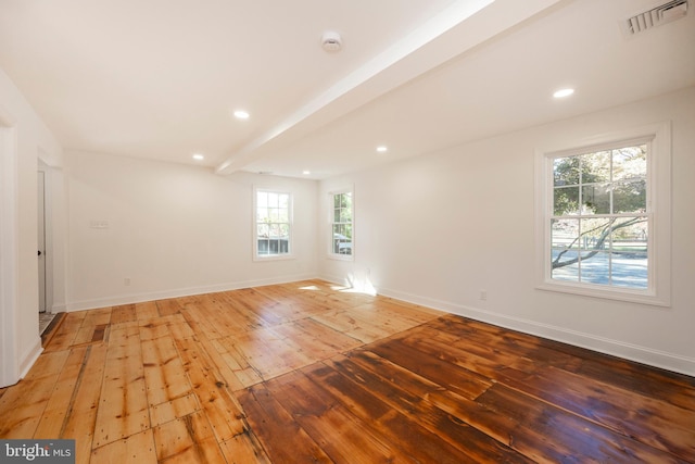 spare room featuring hardwood / wood-style floors and beamed ceiling