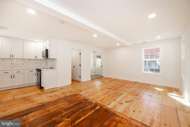 unfurnished living room featuring light hardwood / wood-style floors and beam ceiling