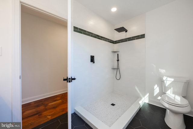 bathroom with toilet, a tile shower, and tile patterned floors