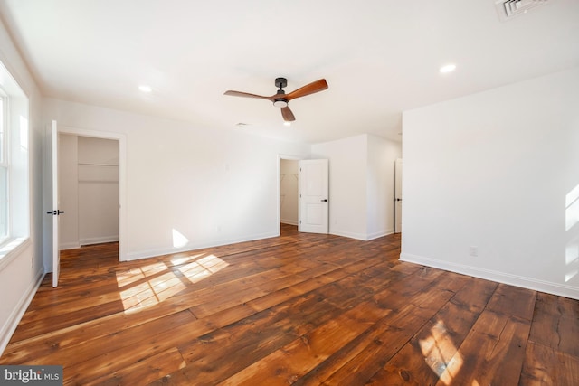 unfurnished bedroom featuring a walk in closet, dark hardwood / wood-style floors, a closet, and ceiling fan