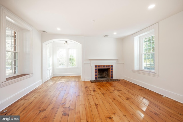 unfurnished living room with light hardwood / wood-style flooring and a tile fireplace