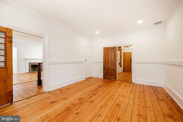 empty room with light hardwood / wood-style flooring, a fireplace, and crown molding