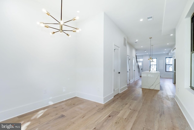 hall with light hardwood / wood-style flooring, a chandelier, and sink