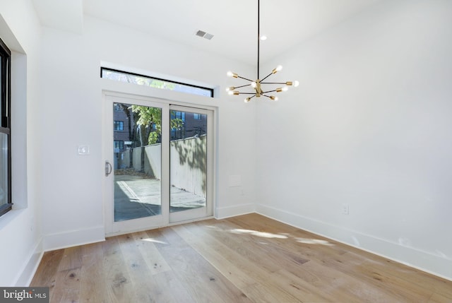 unfurnished room featuring light wood-type flooring and a notable chandelier