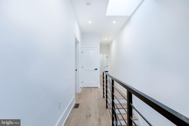 corridor with light hardwood / wood-style flooring and a skylight