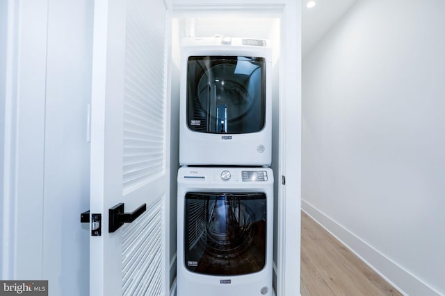 laundry room featuring stacked washer / dryer and light wood-type flooring