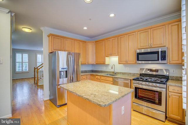 kitchen with a kitchen island, stainless steel appliances, sink, light wood-type flooring, and light stone counters