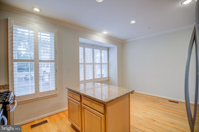 kitchen with a wealth of natural light, crown molding, and light hardwood / wood-style floors