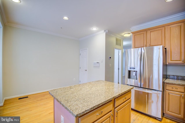 kitchen with ornamental molding, stainless steel fridge, light stone countertops, a center island, and light hardwood / wood-style floors