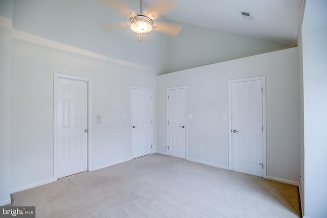 unfurnished bedroom featuring two closets, light colored carpet, high vaulted ceiling, and ceiling fan