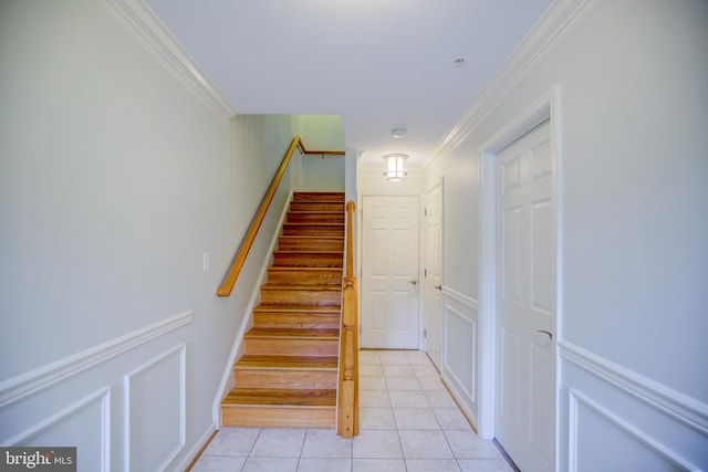 staircase with ornamental molding and tile patterned flooring