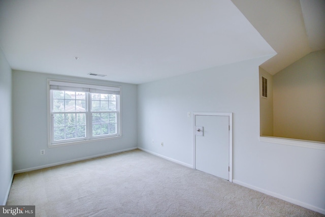 carpeted spare room with vaulted ceiling