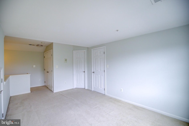 spare room featuring lofted ceiling and light colored carpet