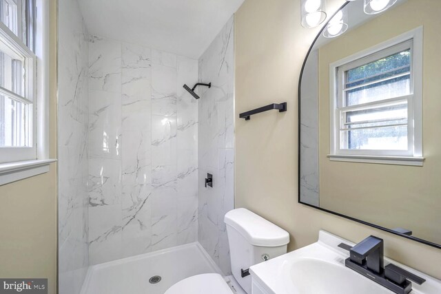 bathroom with vanity, tiled shower, and toilet