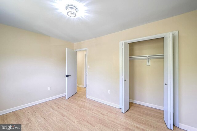 unfurnished bedroom with light hardwood / wood-style flooring and a closet