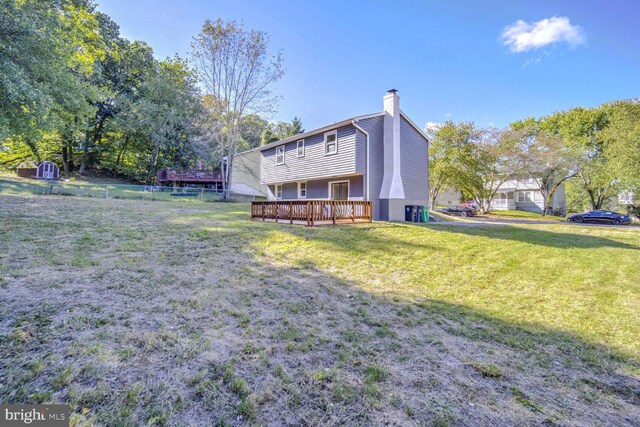 back of property with a storage shed, a deck, and a lawn