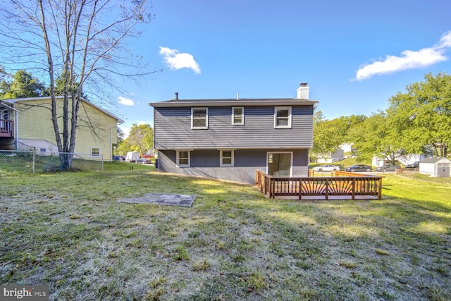 rear view of property featuring a wooden deck, a storage unit, and a lawn