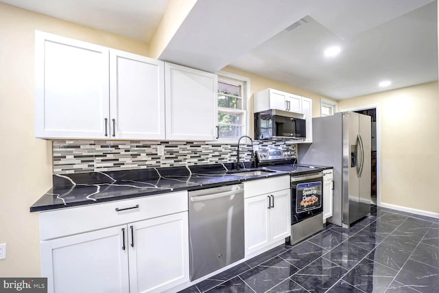 kitchen with decorative backsplash, dark stone countertops, sink, white cabinetry, and appliances with stainless steel finishes