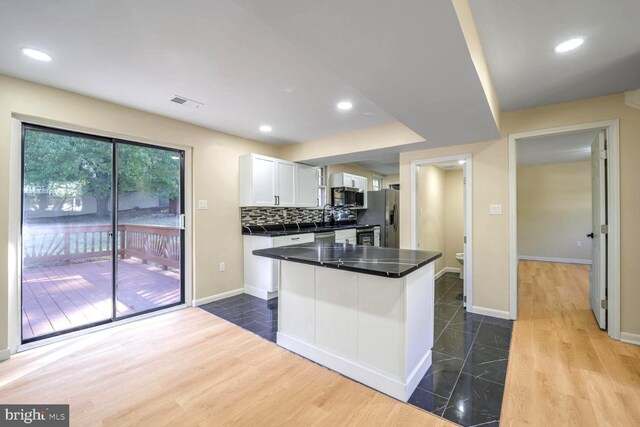 kitchen with decorative backsplash, a kitchen island, hardwood / wood-style flooring, stainless steel appliances, and white cabinets